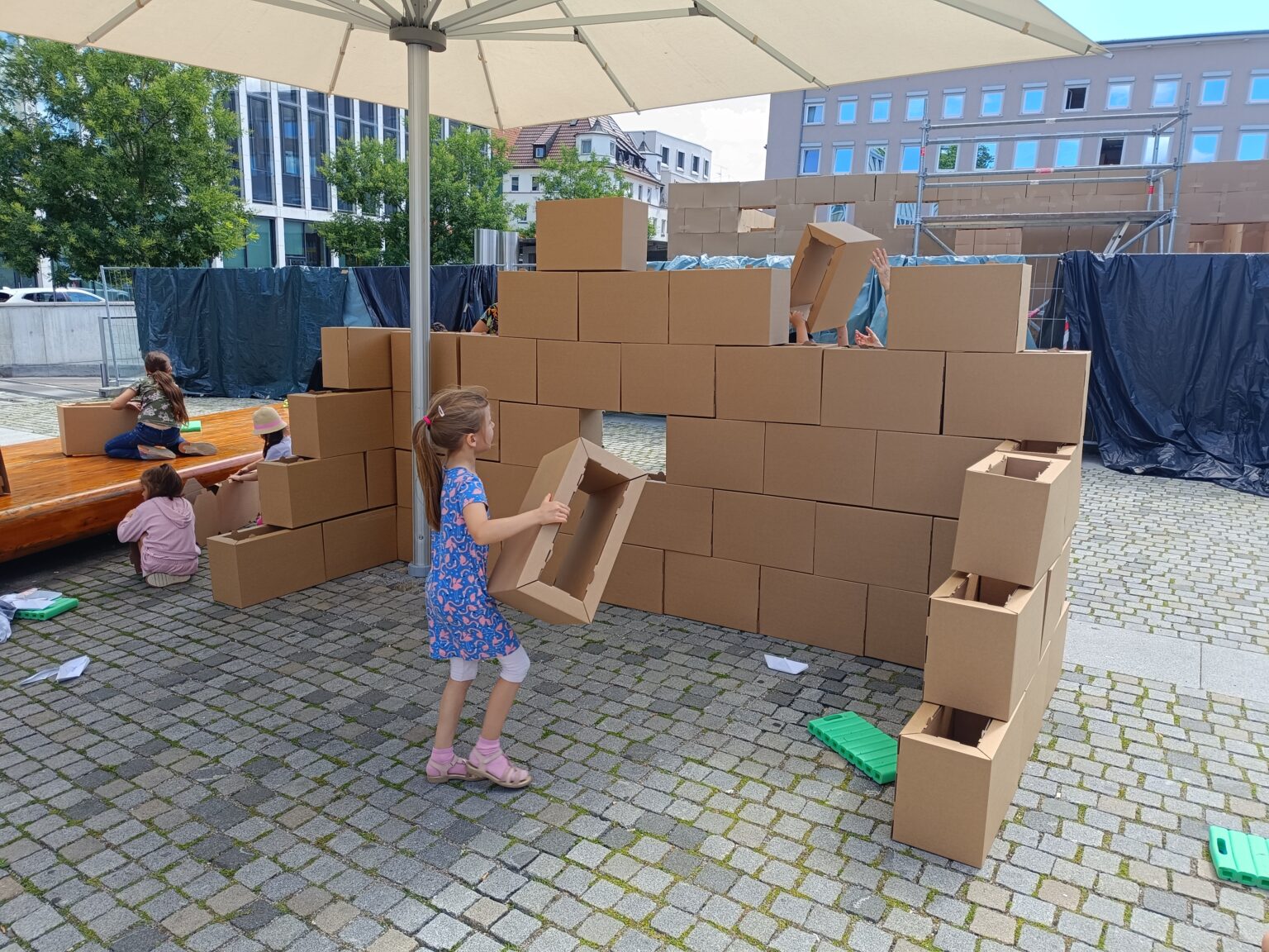 Kinder bauen ein Haus aus Pappsteinen auf